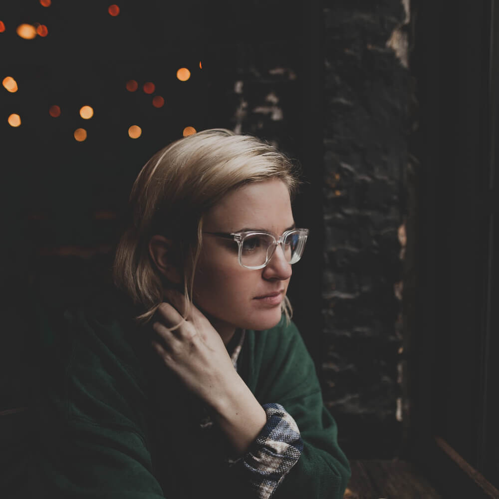 Headshot of woman wearing a green top and sunglasses, looking in the distance.