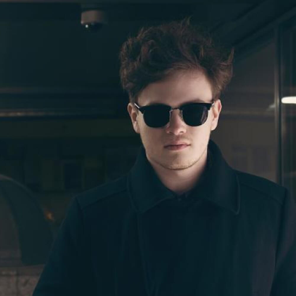 Headshot of man wearing black sunglasses looking into the camera.